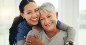 Happy woman, nurse and hug senior patient in elderly care. Primary Care Offer Families