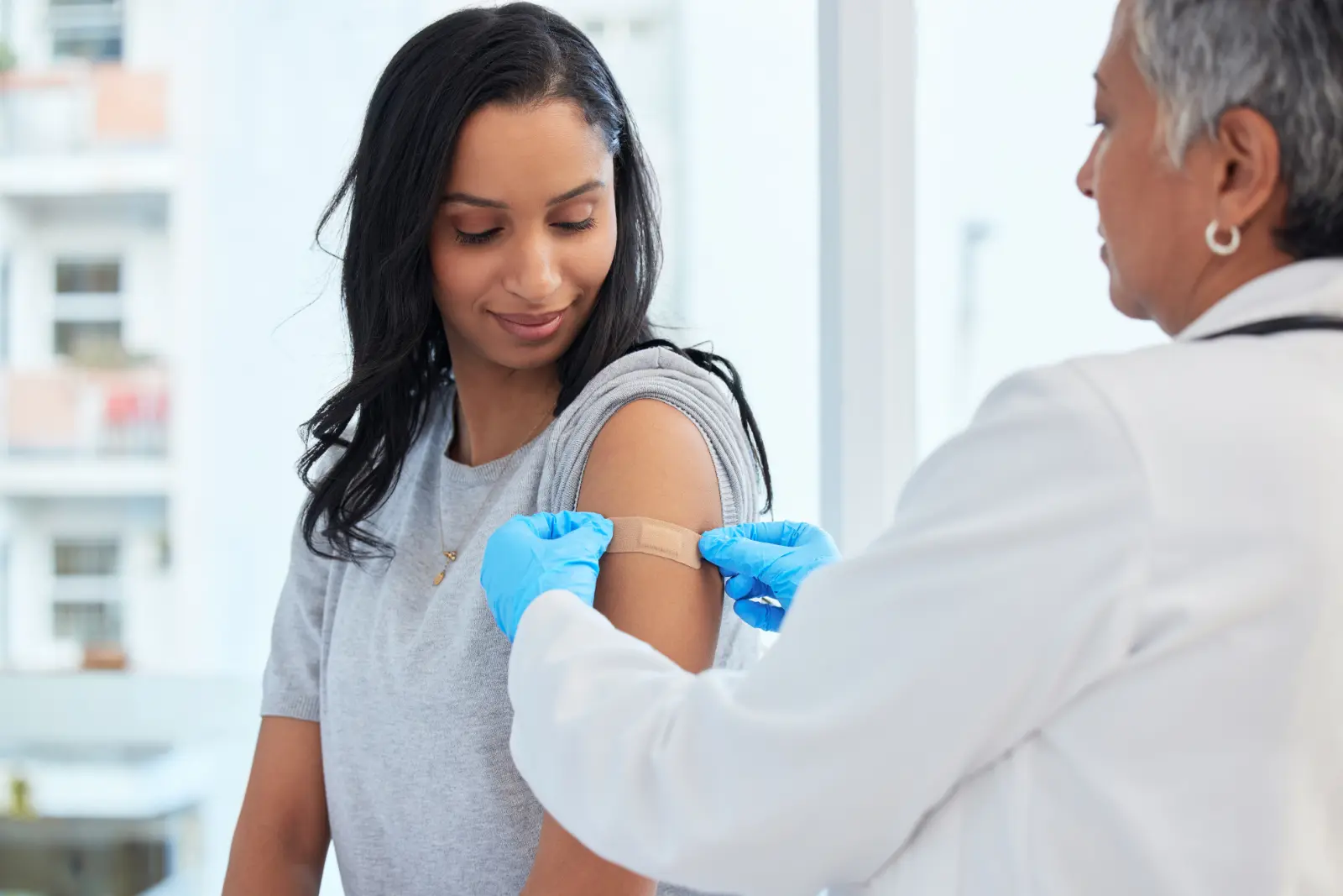 Why Consider DPC nurse applying bandaid to patients shoulder.